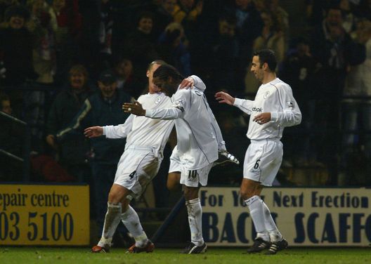 BOLTON, ENGLAND - JANUARY 21: Jay Jay Okocha of Bolton celebrates scoring the fifth goal with Kevin Nolan (L) and Youri Djorkaeff (R) during the Carling Cup Semi-Final First Leg match between Bolton Wanderers and Aston Villa at the Reebok Stadium on January 21, 2004 in Bolton, England. (Photo by Michael Steele/Getty Images)