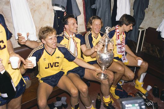 LIVERPOOL, REGNO UNITO - 26 MAGGIO: I giocatori dell'Arsenal (da sinistra) Kevin Richardson, Steve Bould, Paul Merson e Alan Smith festeggiano nello spogliatoio con il trofeo della League Division One dopo che l'Arsenal aveva battuto il Liverpool per 2-0 nell'ultima partita della stagione, strappando il titolo al Liverpool, ad Anfield il 26 maggio 1989 a Liverpool, Inghilterra. (Foto di Allsport/Getty Images) Liverpool-Arsenal, tra miracoli e tragedie: le 5 sfide che hanno fatto la storia- immagine 2