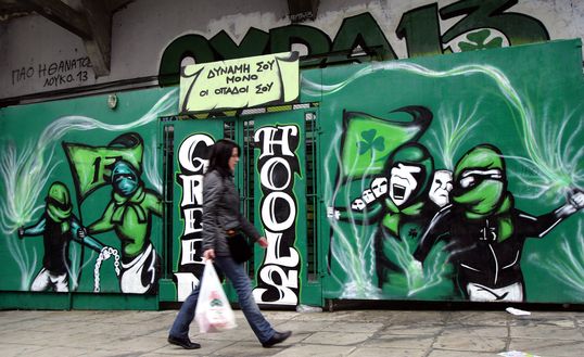 ATENE, GRECIA - 31 MARZO: Una donna passa davanti a un graffito dell'FC Panathenaikos 'Green Hools', raffigurante atti di teppismo contro i tifosi dell'FC Olympakos, nella periferia del Pireo, il 31 marzo 2007 ad Atene, in Grecia. (Foto di Milos Bicanski/Getty Images) Rangers Pana