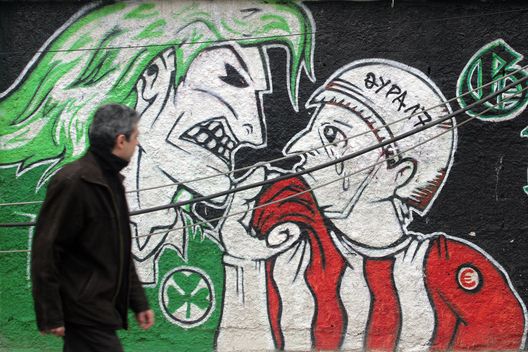 ATENE, GRECIA - 31 MARZO: Un uomo passa davanti a un graffito dell'FC Panathenaikos 'Green Hools', raffigurante atti di teppismo contro i tifosi dell'FC Olympakos, nella periferia del Pireo, il 31 marzo 2007 ad Atene, in Grecia. Le autorità greche hanno annullato tutte le partite di sport di squadra per due settimane dopo una violenta rissa tra tifosi dell'Olympiakos Pireo e del Panathinaikos nei pressi di Atene. Un uomo di 25 anni è morto riportando ferite alla testa e ferite da arma da taglio. (Foto di Milos Bicanski/Getty Images) Olympiakos Panathinaikos coreografie
