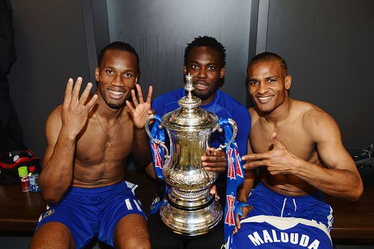 Didier Drogba, Michael Essien e FLorent Malouda del Chelsea festeggiano con il trofeo nello spogliatoio dopo la finale di FA Cup con Budweiser tra Liverpool e Chelsea allo stadio di Wembley il 5 maggio 2012 a Londra, Inghilterra Cuore africano in maglia Chelsea: storie di potenza, talento e gloria- immagine 3