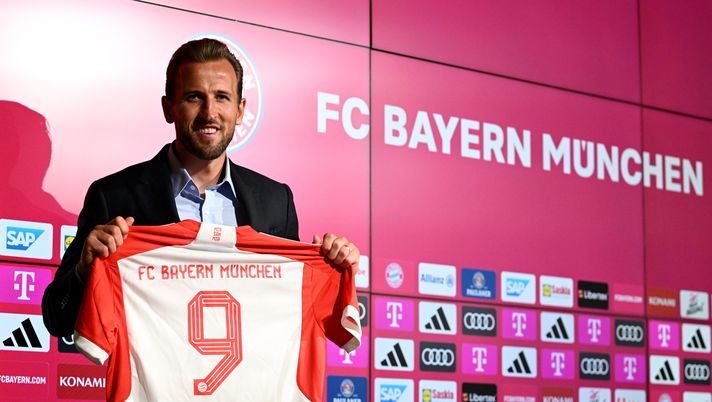 MUNICH, GERMANY - AUGUST 13: Harry Kane of FC Bayern München poses for a photograph whilst holding a FC Bayern München shirt, which reads '9 Kane', after speaking to the media during an official press conference announcing his signing with the club at Presse Club of Allianz Arena on August 13, 2023 in Munich, Germany. The English National forward signed a contract with the club until 2027. (Photo by Christian Kaspar-Bartke/Getty Images) La maledizione di Kane: altro trofeo perso, il Bayern è avvertito? - immagine 1