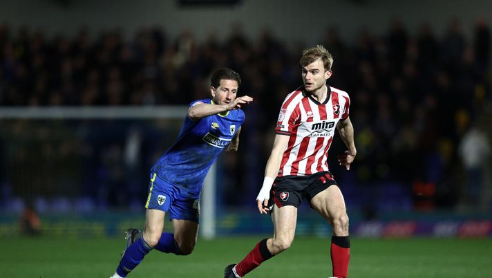 WIMBLEDON, INGHILTERRA - 11 MARZO: George Miller del Cheltenham Town controlla la palla sotto pressione di Sam Hutchinson dell'AFC Wimbledon durante la partita di Sky Bet League Two tra AFC Wimbledon e Cheltenham Town al Cherry Red Records Stadium l'11 marzo 2025 a Wimbledon, Inghilterra. (Foto di James Fearn/Getty Images) Infarto gol