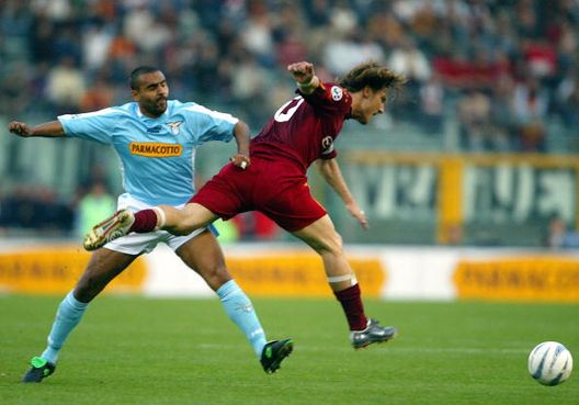 Il capitano della Roma Francesco Totti (a destra) viene placcato dal centrocampista della Lazio Fabio Liverani, durante la partita di calcio di Serie A allo Stadio Olimpico di Roma, il 21 aprile 2004. Il derby si è concluso con un pareggio per 1-1 “Capitano mio capitano”: i capitani storici del derby Lazio-Roma- immagine 3