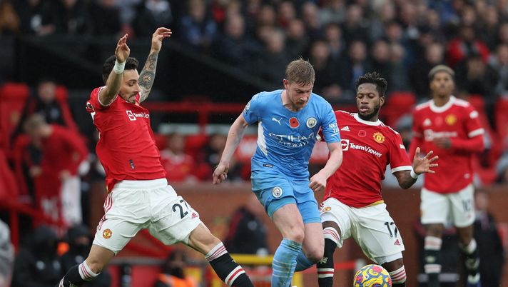 MANCHESTER, ENGLAND - NOVEMBER 06: Kevin De Bruyne of Manchester City runs with the ball from Alex Telles and Fred of Manchester United during the Premier League match between Manchester United and Manchester City at Old Trafford on November 06, 2021 in Manchester, England. (Photo by Clive Brunskill/Getty Images) Manchester City, l’infortunio di De Bruyne mette in dubbio il rinnovo del belga - immagine 1