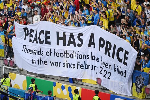 Uno striscione con la scritta 'La pace ha un prezzo, migliaia di tifosi di calcio sono morti nella guerra da febbraio 2022' durante UEFA EURO 2024 . (Foto di Shaun Botterill/Getty Images) calcio ucraino