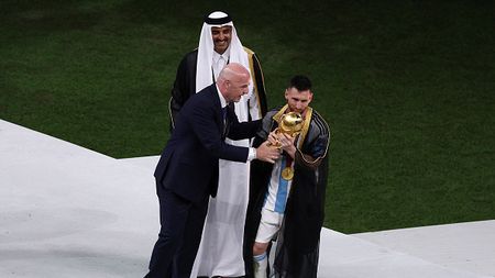 LUSAIL CITY, QATAR - DECEMBER 18: Lionel Messi of Argentina receives the World Cup Trophy from FIFA President Gianni Infantino and Sheikh Tamim bin Hamad Al Thani, Emir of Qatar, during the awards ceremony after the FIFA World Cup Qatar 2022 Final match between Argentina and France at Lusail Stadium on December 18, 2022 in Lusail City, Qatar. (Photo by Richard Heathcote/Getty Images)