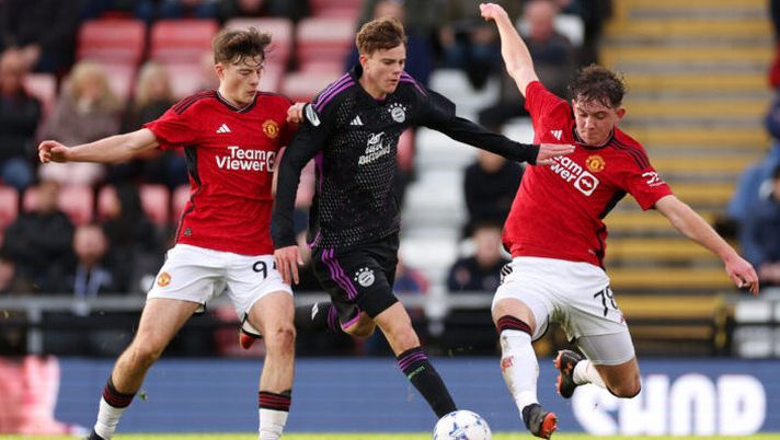 LEIGH, ENGLAND - DECEMBER 12: Jonathan Asp-Jensen of Bayern Munich is challenged by Jayce John Fitzgerald and Louis Jackson of Manchester United during the UEFA Youth League - Group A match between Manchester United and Bayern Munich at Leigh Sports Village on December 12, 2023 in Leigh, England. (Photo by Lewis Storey/Getty Images) Lazio, la verità su Jonathan Asp e la posizione del Bayern Monaco: cosa risulta a Matteo Moretto - immagine 1