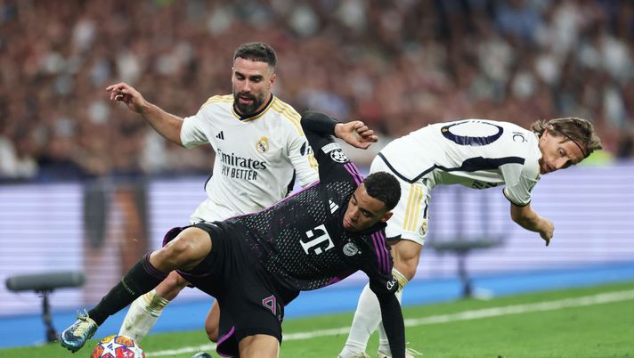 MADRID, SPAIN - MAY 08: Jamal Musiala of Bayern Munich is challenged by Daniel Carvajal and Luka Modric of Real Madrid during the UEFA Champions League semi-final second leg match between Real Madrid and FC Bayern München at Estadio Santiago Bernabeu on May 08, 2024 in Madrid, Spain. (Photo by Clive Brunskill/Getty Images) Real Madrid-Bayern Monaco, statistiche e precedenti del big match di Champions - immagine 1