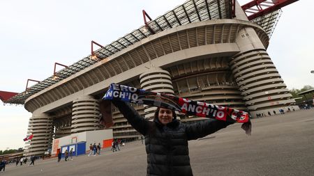 MILAN, ITALY - APRIL 19: A fan poses for a photograph with a half and half scarf outside the Giuseppe Meazza Stadium prior to kick off of the Coppa Italia Semi Final 2nd Leg match between FC Internazionale v AC Milan at Giuseppe Meazza Stadium on April 19, 2022 in Milan, Italy. (Photo by Marco Luzzani/Getty Images)