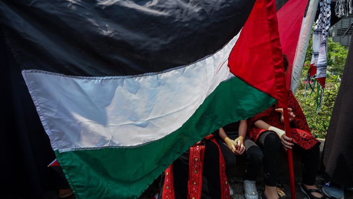 KUALA LUMPUR, MALAYSIA - OCTOBER 13: A a Palestinian flag shields a group of children during a protest rally as Malaysian Muslim activists and Palestinian nationals gather to express solidarity with the people of Palestine, marching toward the US Embassy after Friday prayers on October 13, 2023 in Kuala Lumpur, Malaysia. Malaysians gathered to protest in solidarity with the Palestinians in the wake of the conflict between Israel and Hamas in the Gaza Strip. On October 7, the Palestinian militant group Hamas launched the largest surprise attack from Gaza in a generation, sending thousands of missiles and an unknown number of fighters by land, who shot and kidnapped Israelis in communities near the Gaza border. The attack prompted retaliatory strikes on Gaza and a declaration of war by the Israeli prime minister. (Photo by Annice Lyn/Getty Images) Algeria, solidarietà al popolo palestinese: sospeso ogni evento calcistico - immagine 1